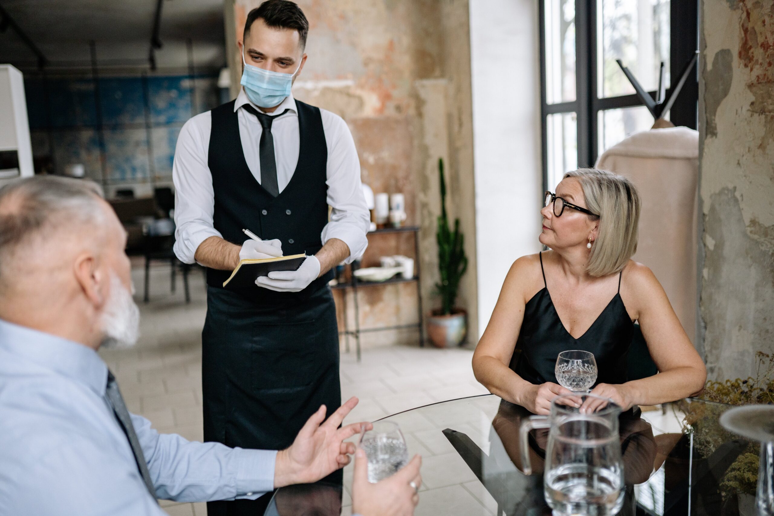 waiter in a medical protective mask serves the coffee in restau