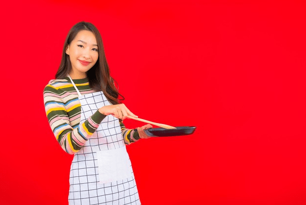 Picture of a korean woman showing how to cook with a red background. 