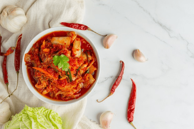 Picture of delicious ready-to-eat kimchi in a bowl with spices around.