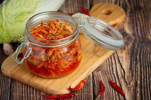 Kimchi in a transparent glass jar.