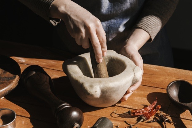 woman hand grinding pepper in a mortar and pestle.