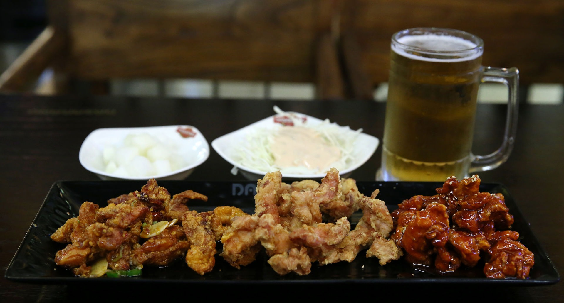 Image of Korean fried chicken in three platters on a table.