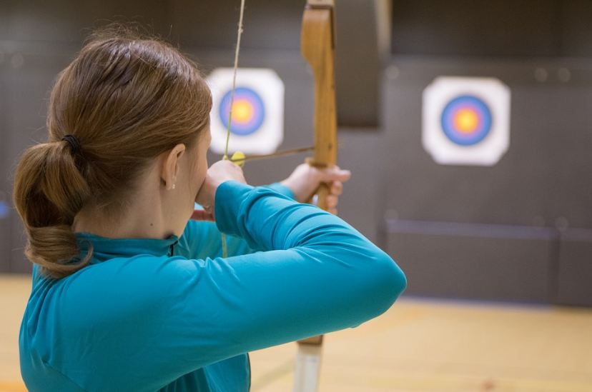 Picture of a woman aiming with an arrow in a hunting bow.