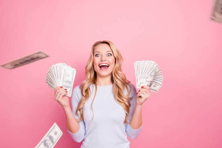 Wow, omg! Portrait of impressed glad girl having a lot of flying money around her, having unbelievable unexpected reaction, isolated on pink background