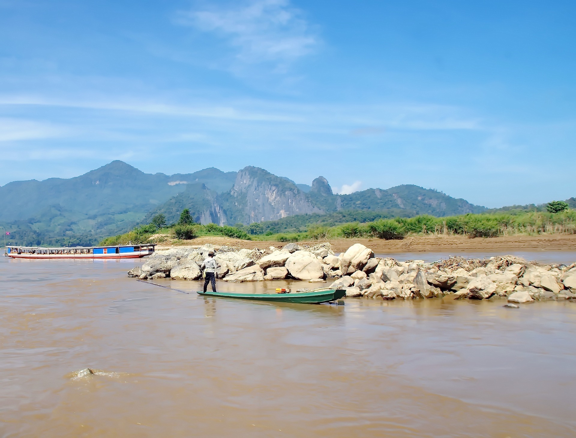 huge-rocks-on-the-river-and-a-fisherman-standing-on-his-boat
