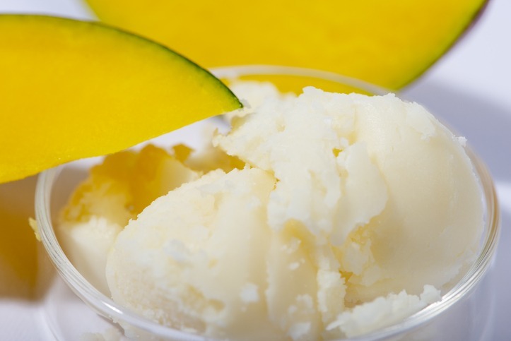 Mango butter and fresh mango fruit close up. Organic cosmetic, skin care, spa concept.
