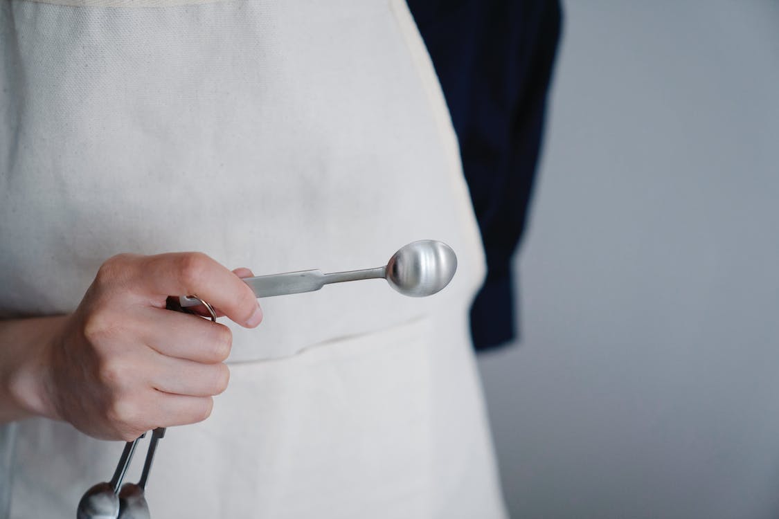 close-up-shot-of-a-person-holding-a-measuring-spoon