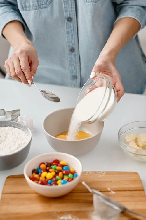 person-pouring-powdered-sugar-in-a-bowl