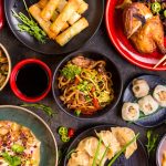Chinese noodles, fried rice, dumplings, peking duck, dim sum, spring rolls on the table